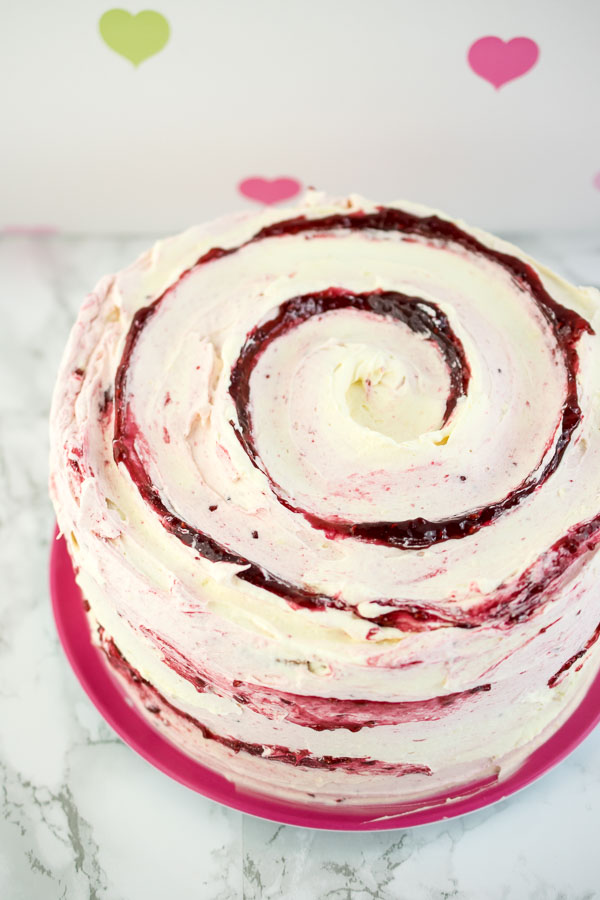 Raspberry Ripple Cake - a light and fluffy vanilla cake filled with raspberry jam and frosted with ripples of both white chocolate and raspberry Italian meringue buttercream