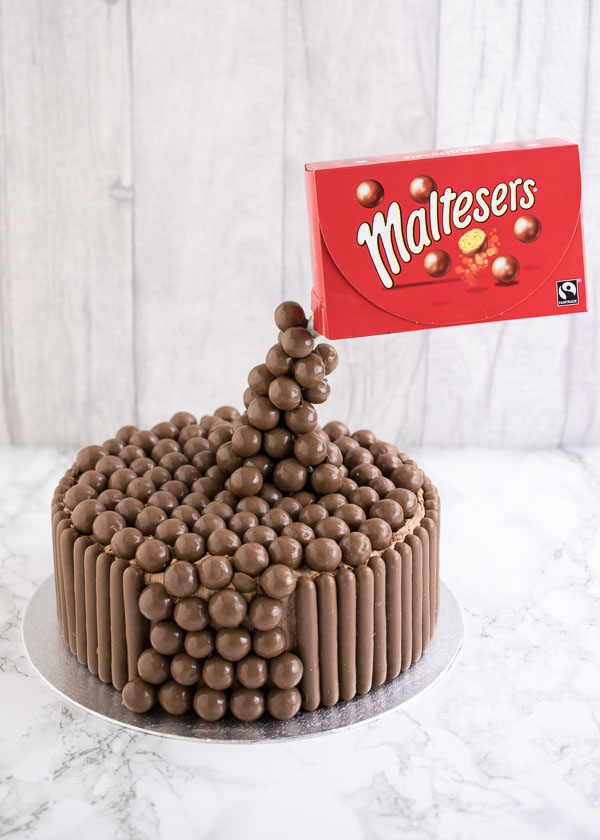 Malteser Anti-Gravity Cake. A chocolate fudge cake filled with Malteser buttercream, topped with lots of Maltesers and covered with Cadbury's fingers around the outside.