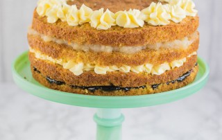 A layer cake on a jade cake stand - layers of vanilla custard sponge, blackcurrant jam, custard buttercream and apple compote. Perfect for autumn.